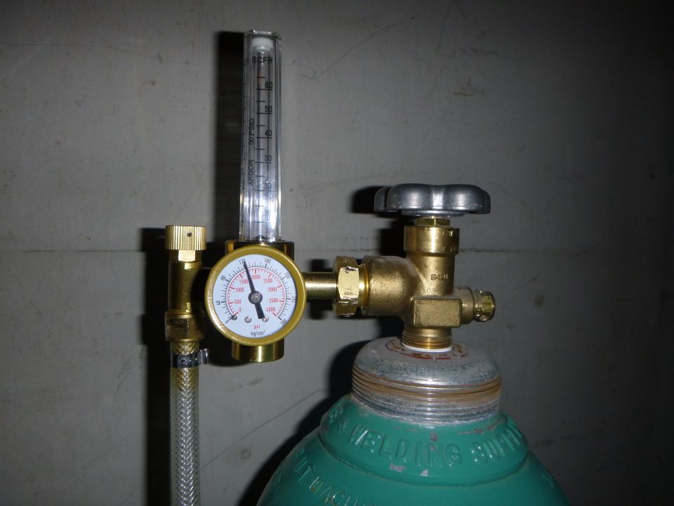 Green gas cylinder with brass regulator, pressure gauge, and flow meter attached