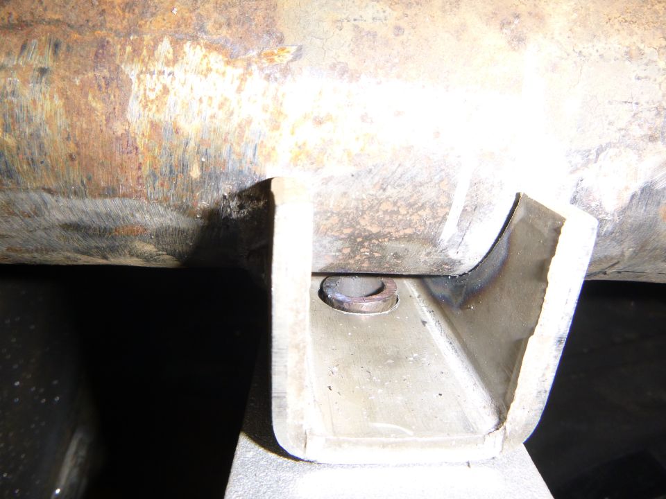 Close-up of a rusty metal pipe with a U-shaped bracket attached