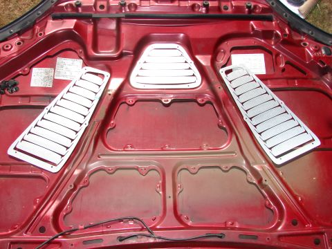1993 Mazda MX-3 - The underside of a car hood shows aftermarket vent covers, but no year-specific details are visible.