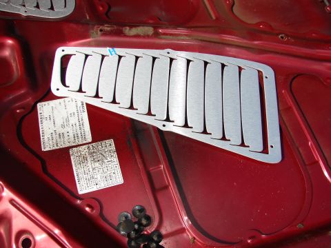 1993 Mazda MX-3 - Aftermarket hood vent installed on the interior of a red vehicle's hood.