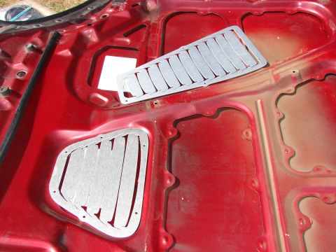 1993 Mazda MX-3 - Aftermarket vent inserts are shown installed on the underside of a red car hood.