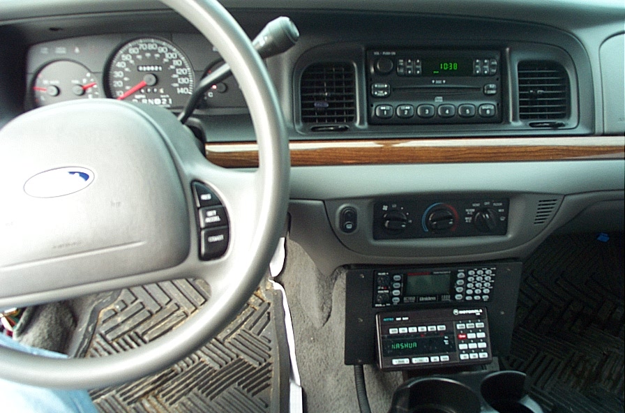 Ford Crown Victoria gray dashboard with Uniden scanner and Motorola radio head reading NASHUA