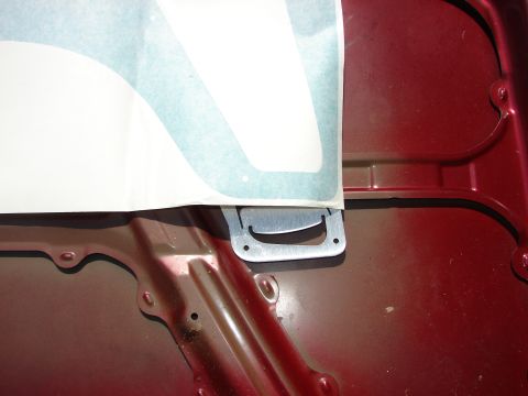 1993 Mazda MX-3 - Close-up of a car's hood interior, showing a metal latch mechanism and a sticker.