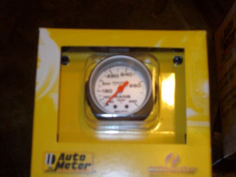 2004 Ford Crown Victoria - Close-up of an Auto Meter gauge, likely for temperature, displayed in its yellow retail packaging.