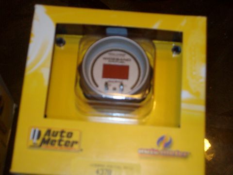 2004 Ford Crown Victoria - Close-up of an Auto Meter gauge in its original packaging, showing a red digital display.