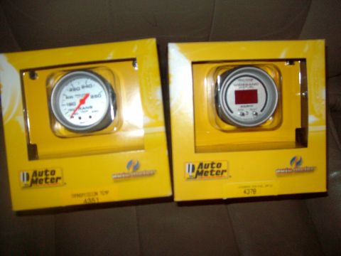 2004 Ford Crown Victoria - Two Auto Meter gauges, one analog and one digital, are displayed in their yellow retail packaging.
