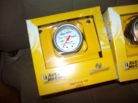 2004 Ford Crown Victoria - An Auto Meter transmission temperature gauge is shown in its yellow retail packaging, with a second box visible to the right.