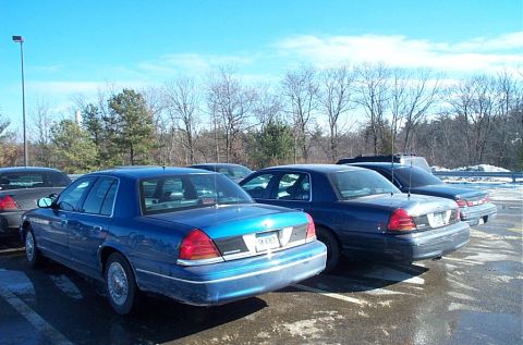 1991 Ford LTD Crown Victoria - Several Ford Crown Victoria police cruisers are parked in a lot on a sunny day.