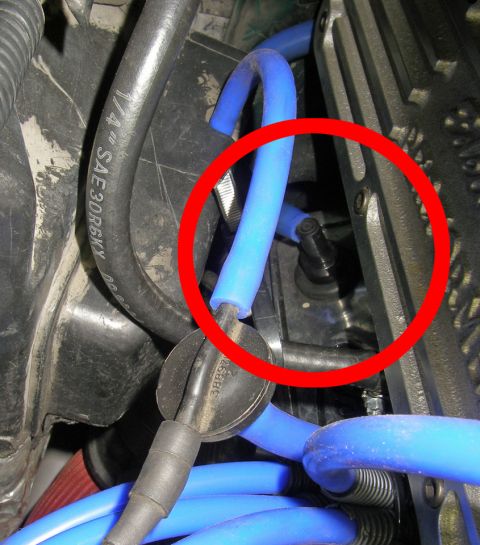1990 Ford Bronco - Close-up view of engine components, including spark plug wires and hoses, with a red circle indicating a specific part.