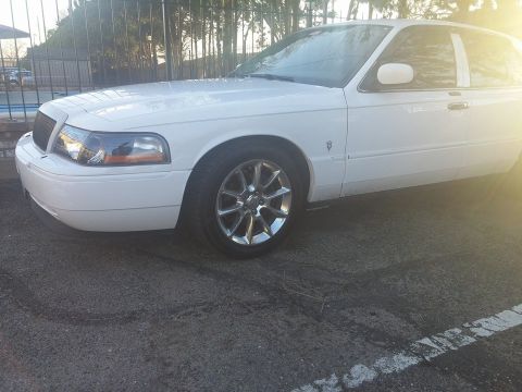 2000 Mercury Grand Marquis - A white sedan is viewed from the front three-quarter angle, parked on a paved surface.