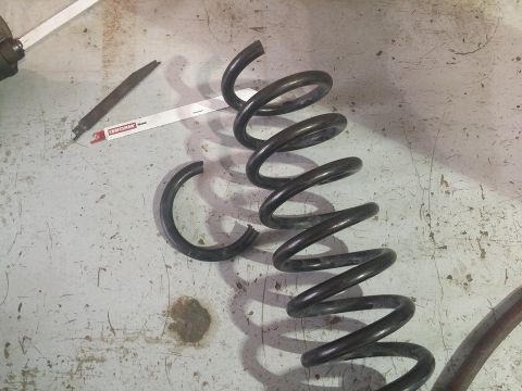 2000 Mercury Grand Marquis - A broken coil spring lies on a workbench next to a hacksaw blade, indicating a repair or replacement process.
