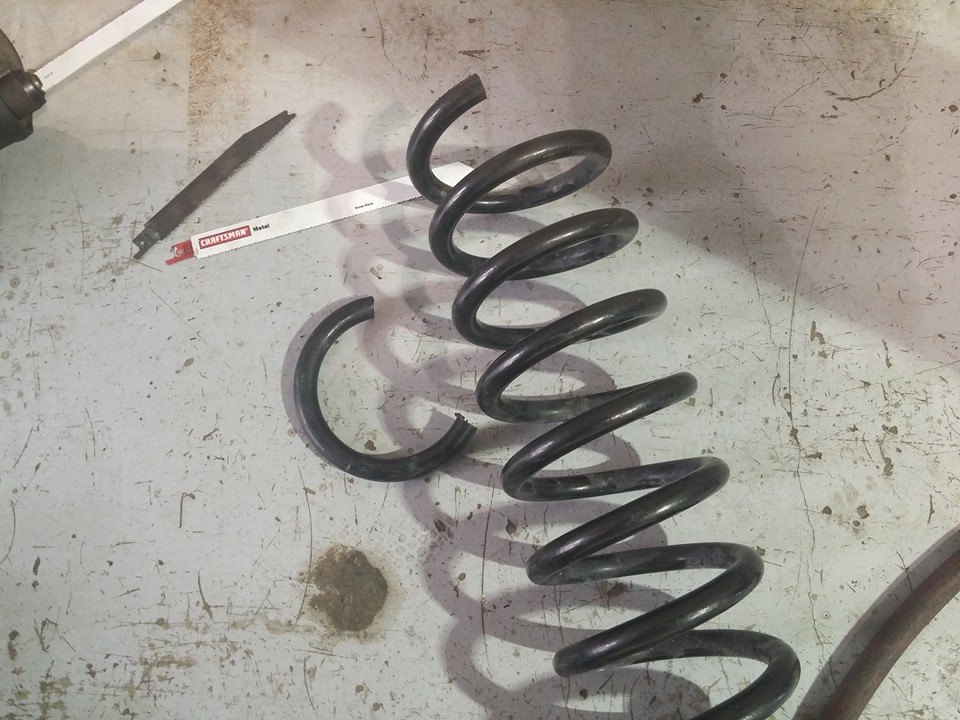 Broken coil spring on a workbench with a hacksaw blade