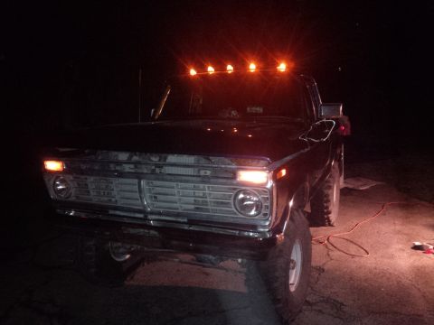 1978 Ford Bronco - A Ford truck is parked outside at night, illuminated by its own lights and an external light source.