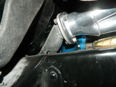 1979 Ford Bronco - Close-up view of an exhaust pipe connection, showing a blue-painted engine component underneath.