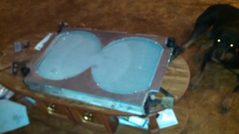 1967 Ford F-250 - A vehicle radiator with a metal frame and two large circular openings sits on a table.