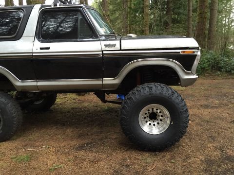 1971 Ford F-250 - This lifted SUV features a two-tone black and silver paint scheme with prominent off-road tires, suggesting a model from the late 1970s.