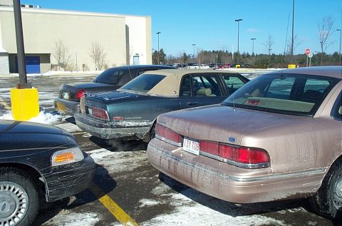1991 Ford LTD Crown Victoria - Multiple Ford Crown Victorias parked in a lot during winter, one with a tan finish.
