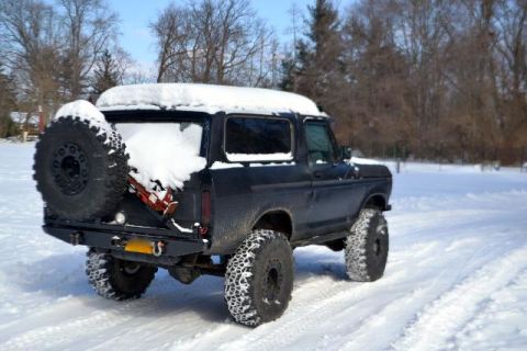 1979 Ford Bronco - This black SUV, likely a 1978 model, is seen in a snowy landscape with snow covering its roof and spare tire.