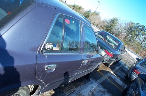 1991 Ford LTD Crown Victoria - A dark blue sedan is parked in a lot with other vehicles visible. A sticker with 'CVN' and an American flag is on the rear door.