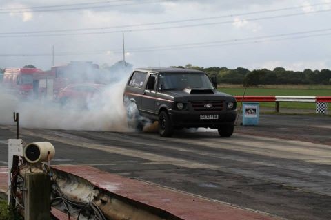 1989 Ford Bronco - A black 1989 Ford Bronco performs a burnout on a drag strip, kicking up a large cloud of smoke.