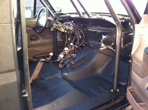 1995 Ford Bronco - The interior of a vehicle shows exposed wiring and a roll cage, suggesting a custom build or modification.