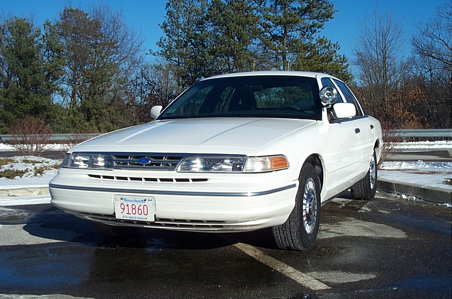 White Ford Crown Victoria police car parked outside, front view. License plate reads 91860