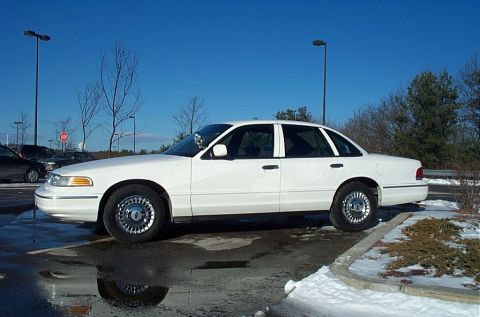 1991 Ford LTD Crown Victoria - Side view of a white sedan with a police light bar on the roof.