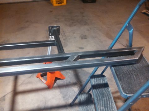 1991 Ford Bronco - A metal frame, possibly for a vehicle modification, is supported by jack stands in a garage.