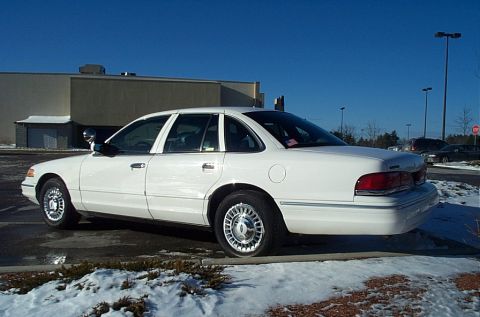 1991 Ford LTD Crown Victoria - A white 1991 Ford Crown Victoria LTD sedan is parked on a snowy lot under a clear blue sky.