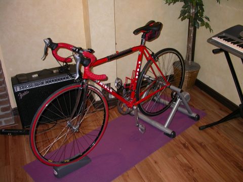 1968 Chevrolet Camaro - A red bicycle is set up on a trainer indoors, next to a Fender amplifier and a keyboard.