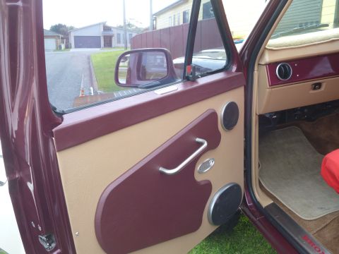 1985 Ford Bronco - The interior door panel features a two-tone design with maroon accents and a chrome door handle.