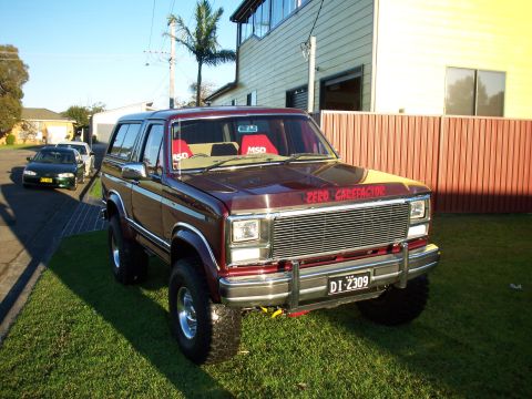 1985 Ford Bronco - This lifted Ford Bronco has a custom grille and red interior seats visible.