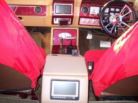 1985 Ford Bronco - Customized 1985 Ford Bronco interior features red seat covers and aftermarket accessories.