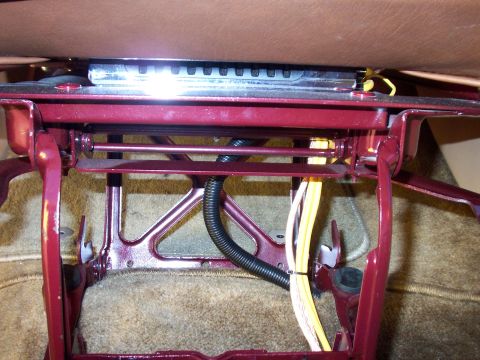 1985 Ford Bronco - The underside of a vehicle seat shows its mechanical components and wiring harness.
