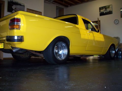 1985 Ford Bronco - Side view of a yellow pickup truck with custom wheels and exhaust.