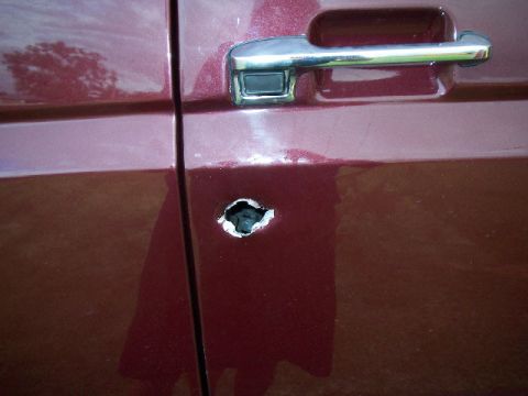 1985 Ford Bronco - This 1985 Ford Bronco door has sustained damage, with a hole punched through the metal.