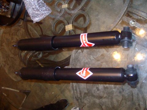 2004 Ford Crown Victoria - Two black shock absorbers with red and white logos are displayed on a table.