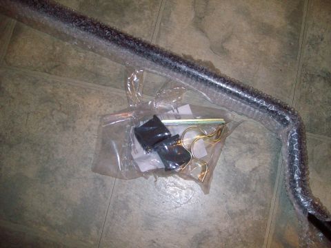 2004 Ford Crown Victoria - A new sway bar and its mounting hardware are laid out on a floor, ready for installation.