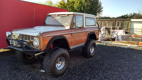 1985 Jeep CJ7 - This 1975 Ford Bronco is parked outdoors on a gravel lot next to a red wall.