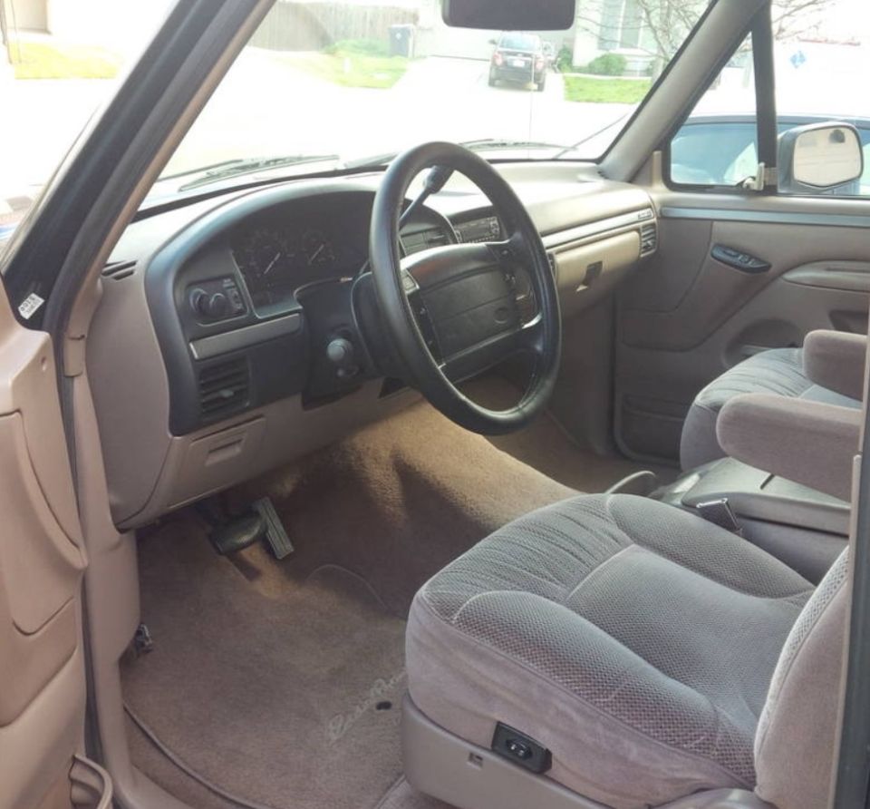 Tan interior of a 1992 Ford Bronco with cloth seats, dashboard, and steering wheel visible