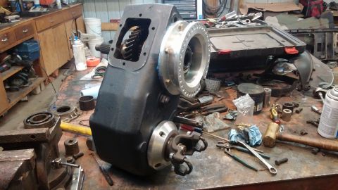 1995 Ford Bronco - Transfer case assembly on a workbench, surrounded by various tools and automotive parts.