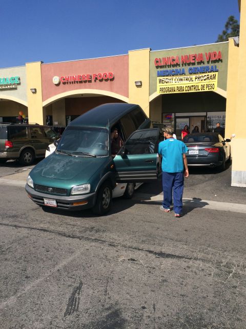 1968 Ford Mustang - A green Toyota RAV4 is parked with its doors open, while a person in blue scrubs walks away from it.