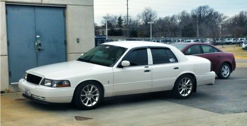 2000 Mercury Grand Marquis - A white sedan is parked in front of a building, with another car visible behind it.