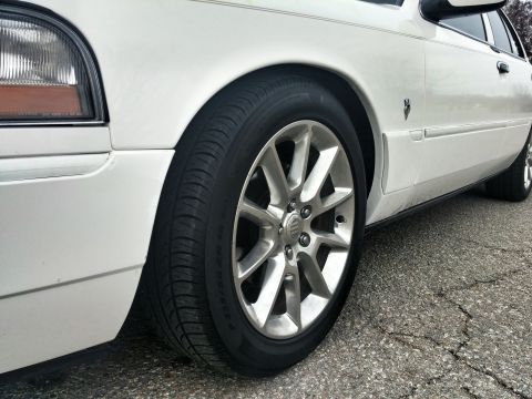 2000 Mercury Grand Marquis - Front quarter view of a white 2000 Mercury Grand Marquis, highlighting its alloy wheel and fender detail.
