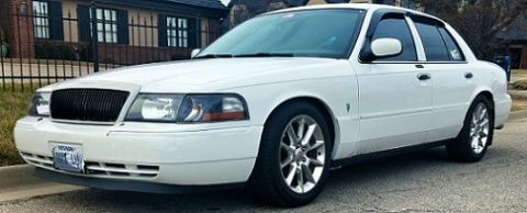 2000 Mercury Grand Marquis - This white sedan features a distinctive black grille and alloy wheels, seen parked on a street.