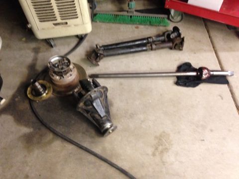 1987 Suzuki Samurai - Various automotive drivetrain components, including a differential and driveshafts, are visible on the floor.