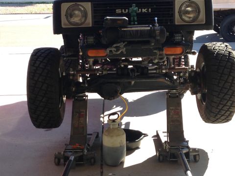 1987 Suzuki Samurai - Front axle of a 1987 Suzuki Samurai being serviced, with a winch mounted on the front.