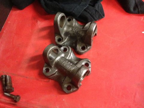 1987 Suzuki Samurai - Two drive shaft yokes are shown on a red surface, with bolts to the side. Part numbers are visible on the yokes.