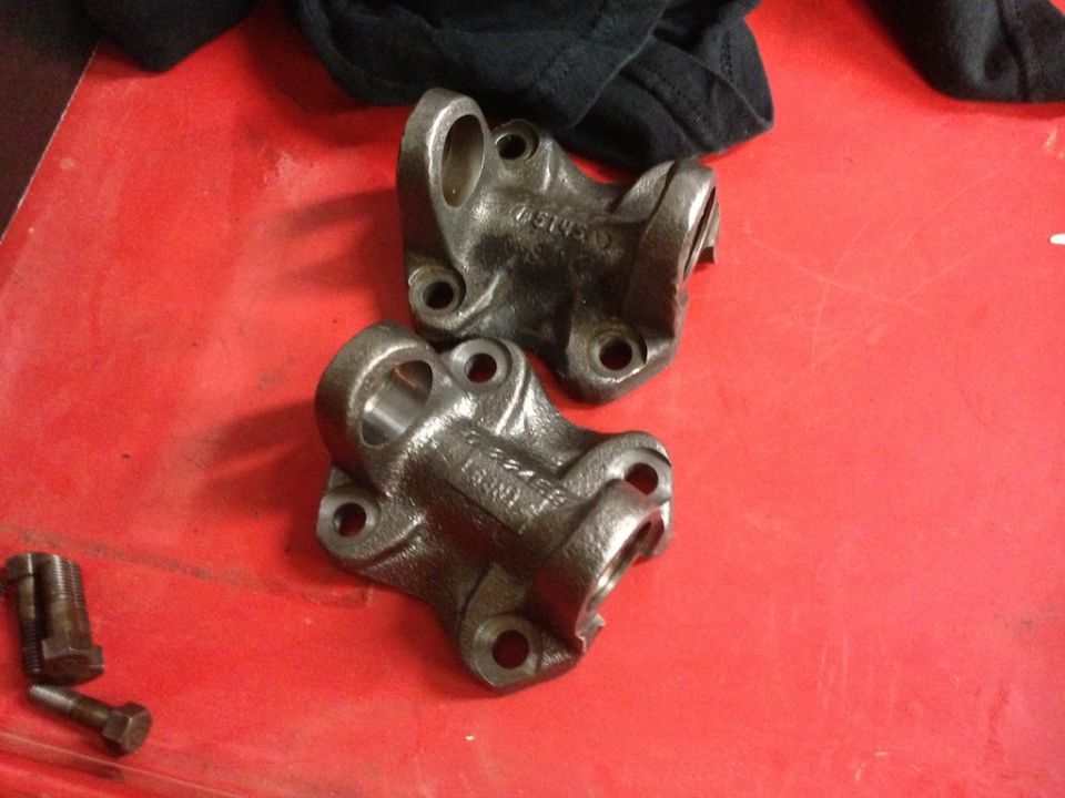Two drive shaft yokes with part numbers visible, next to bolts