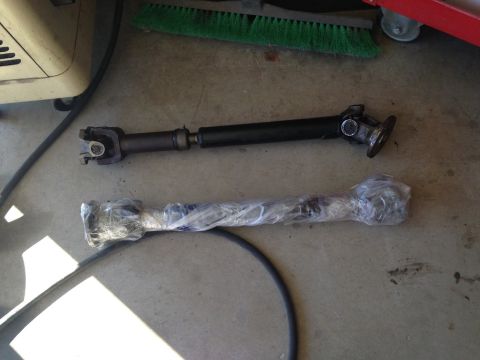 1987 Suzuki Samurai - Two drive shafts are shown on a concrete floor, one appears used and the other is new.